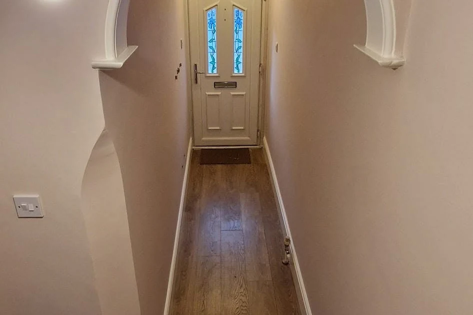hallway-painting-southampton-southampton-decorators Narrow hallway with pale walls, wooden floor and a glazed front door at the far end
