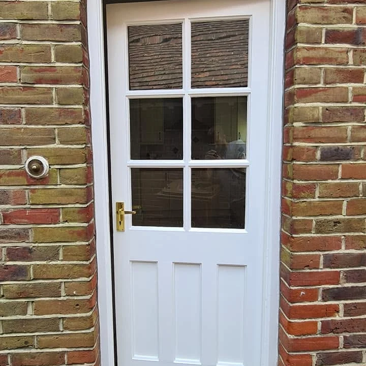 Freshly painted white timber front door with six glazed panes and brass hardware