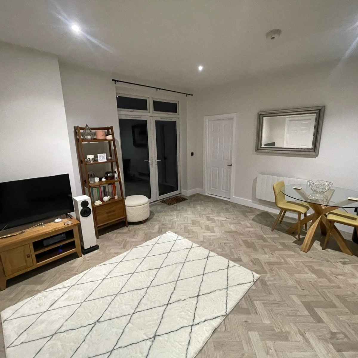 Freshly decorated living room with soft grey walls, mirror and patterned rug